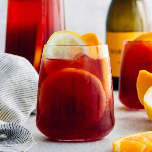 A glass of tinto de verano with a bottle of wine behind it.