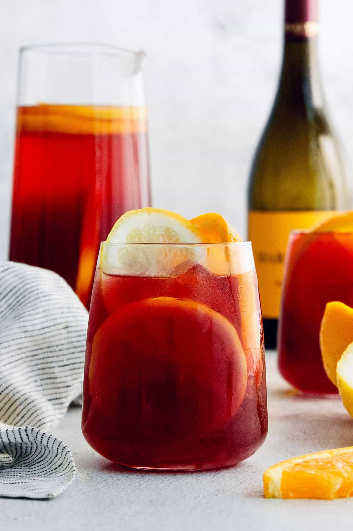 Tinto de Verano, a Spanish summertime cocktail, features fruity red wine, lemon soda, and red vermouth served over ice. A glass of tinto de verano with a bottle of wine behind it.