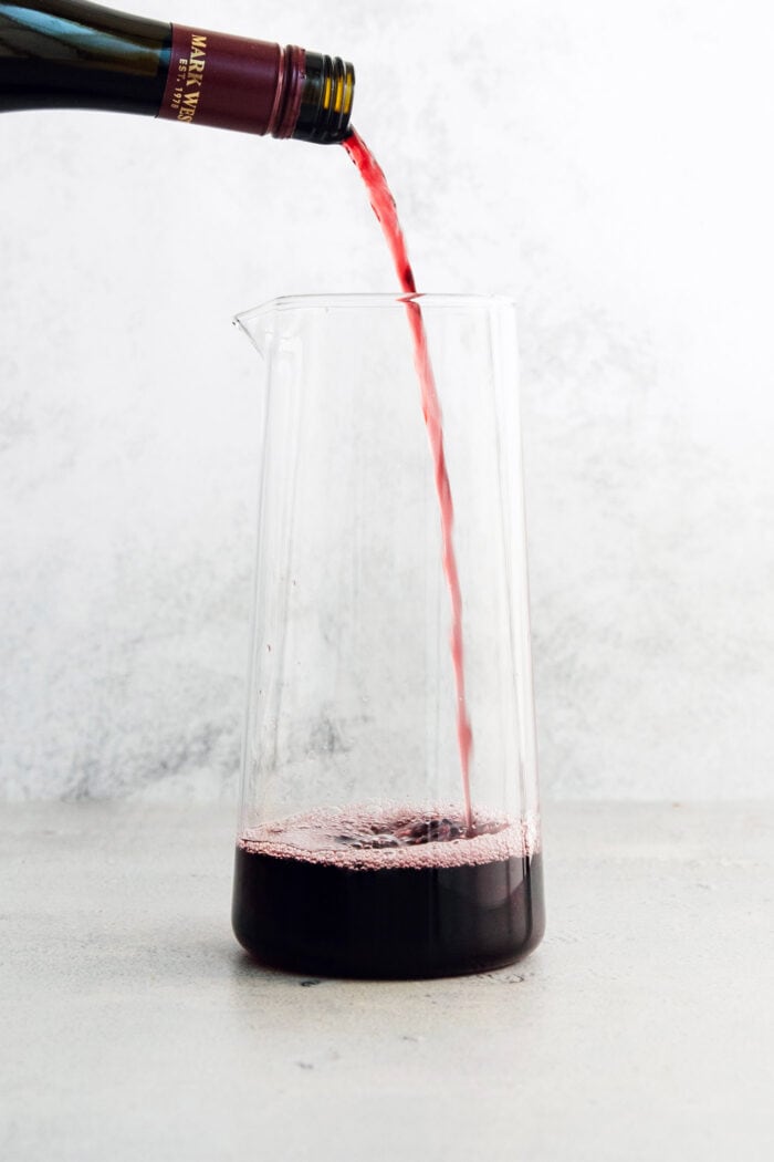 Tinto de Verano, a Spanish summertime cocktail, features fruity red wine, lemon soda, and red vermouth served over ice. Red wine is poured into the pitchers.