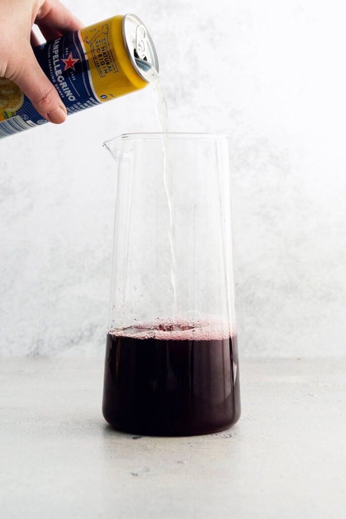 Tinto de Verano, a Spanish summertime cocktail, features fruity red wine, lemon soda, and red vermouth served over ice. Lemon soda is added to the pitcher.