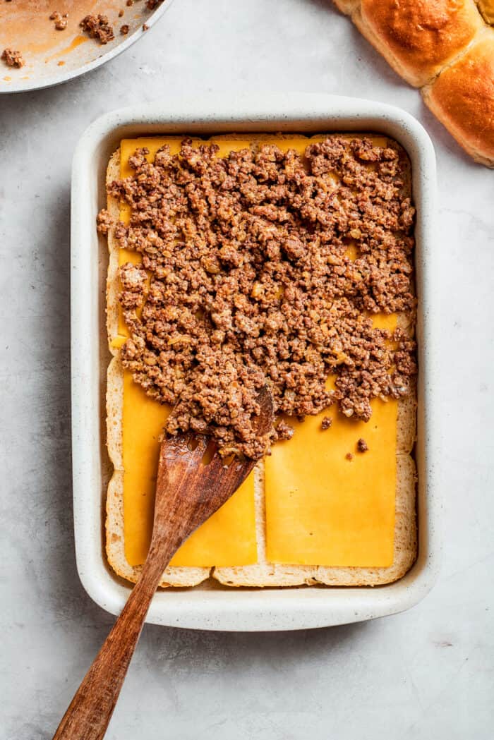 Homemade Cheeseburger Sliders star tender ground beef topped with plenty of melted cheddar cheese served on sweet rolls. Ground beef is added to rolls and cheese.