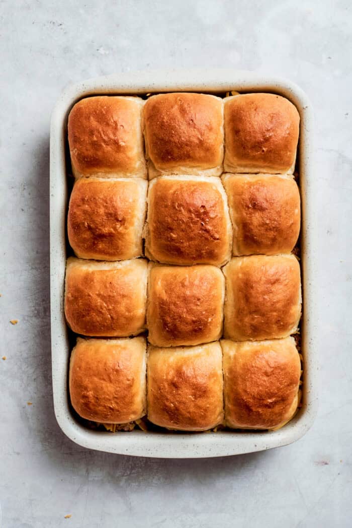 Homemade Cheeseburger Sliders star tender ground beef topped with plenty of melted cheddar cheese served on sweet rolls. A pan of baked cheeseburger sliders.