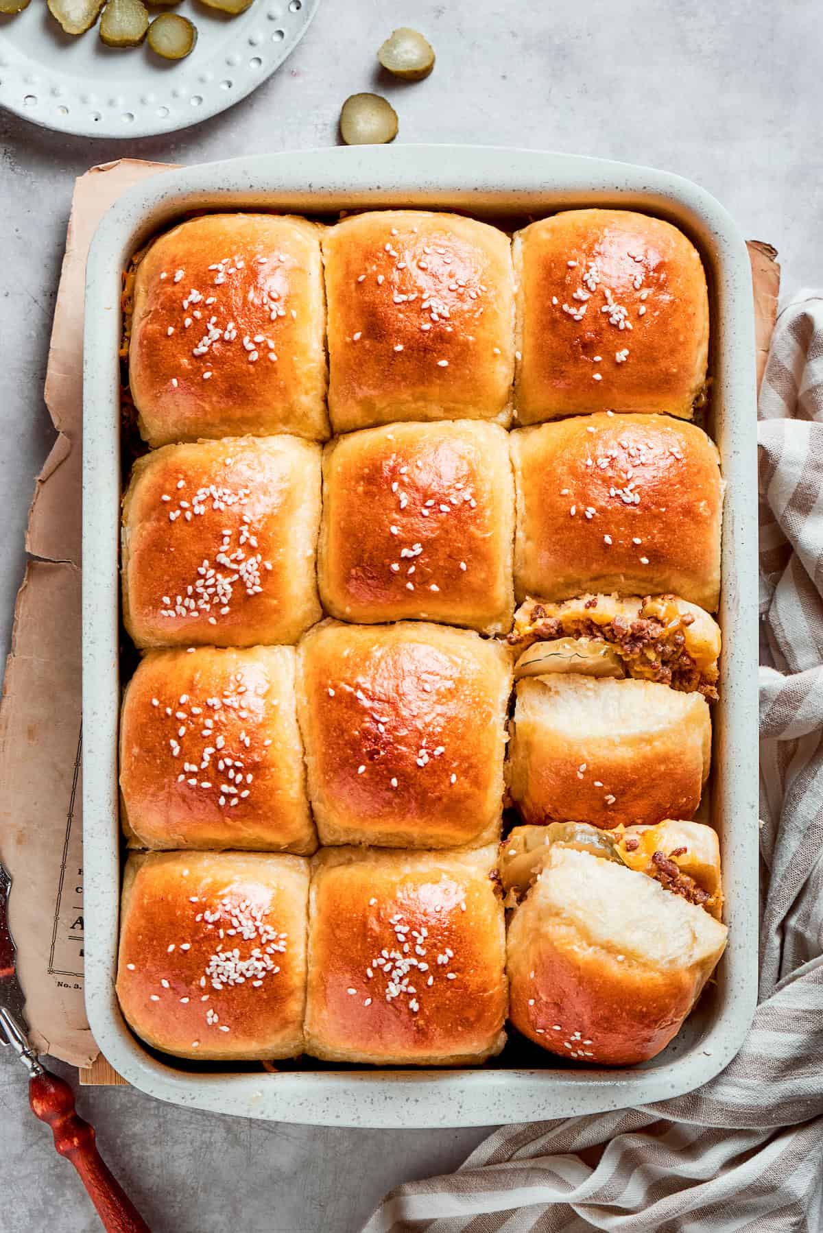 Homemade Cheeseburger Sliders star tender ground beef topped with plenty of melted cheddar cheese served on sweet rolls. A pan of 12 baked cheeseburger sliders in a pan.