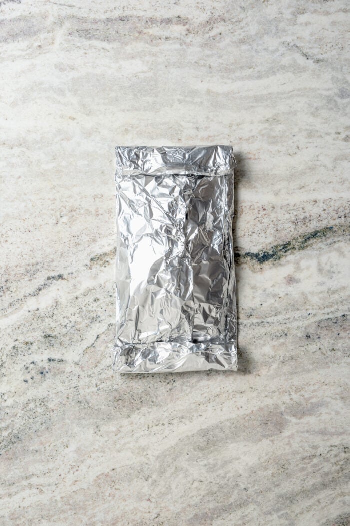 Savory Grilled Potato Packets feature grilled potatoes in foil dressed in tangy, garlicky pesto-ranch sauce and ready in less than 30 minutes. Foil encloses potatoes.