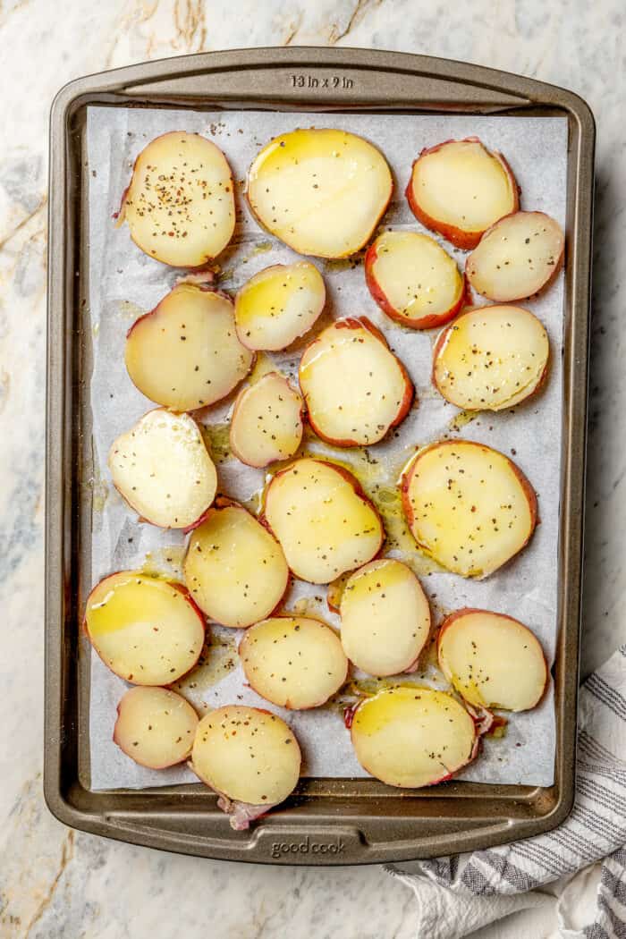 Crisp-tender Grilled Red Potatoes are spiked with the brisk flavors of dill, feta cheese, and lemon and grilled to perfection. Slices of red potatoes on a baking tray.