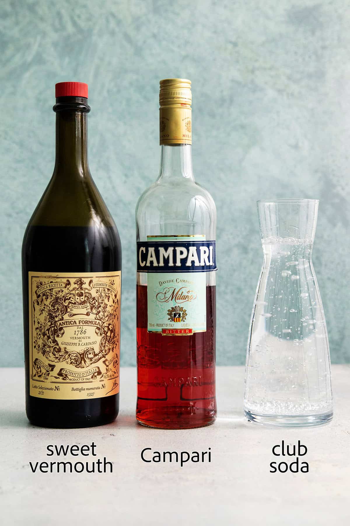This 3-ingredient Americano Cocktail is made from equal parts Campari and sweet vermouth plus a splash of bubbly club soda. The ingredients for Americano cocktail are labeled: sweet vermouth, Campari, club soda.