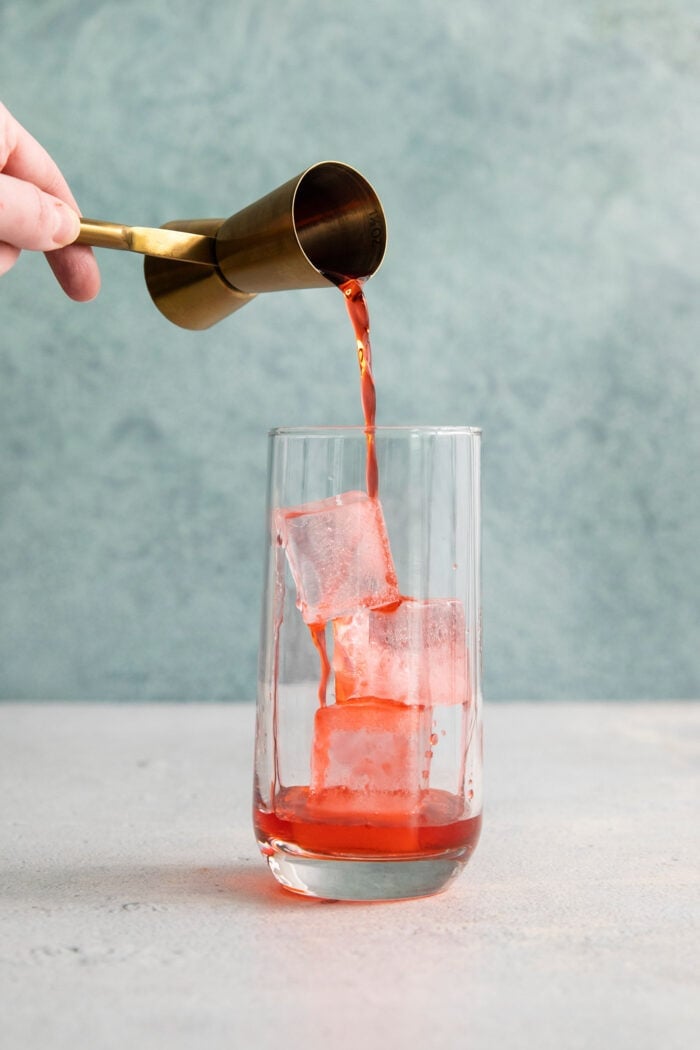 This 3-ingredient Americano Cocktail is made from equal parts Campari and sweet vermouth plus a splash of bubbly club soda. Campari is poured over a glass of ice.