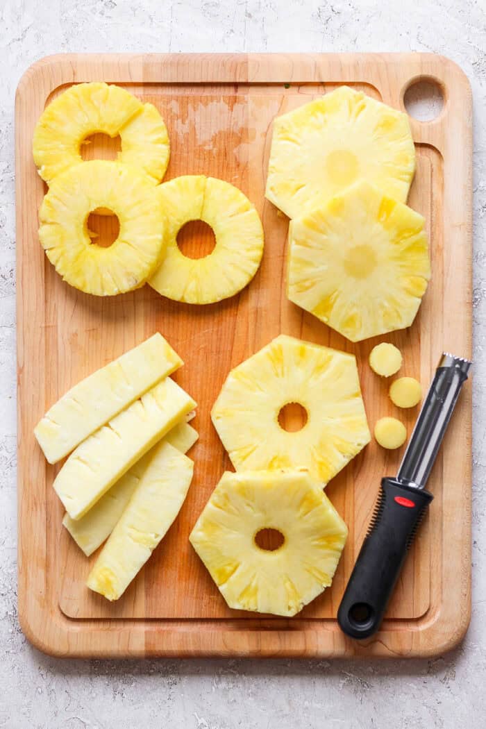 Lightly caramelized and so juicy Grilled Pineapple is a blend of sweet and spicy, perfect on top of burgers or as a dessert. The core is removed from rings of pineapple on a cutting board.