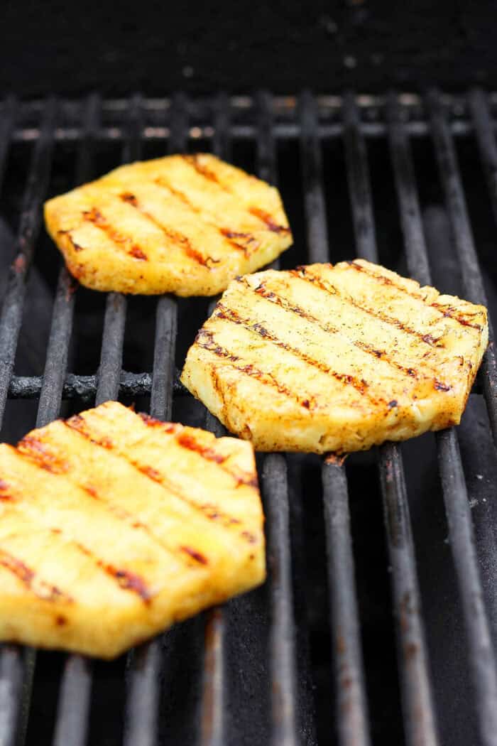 Lightly caramelized and so juicy Grilled Pineapple is a blend of sweet and spicy, perfect on top of burgers or as a dessert. Slices of pineapple cool on the grill.