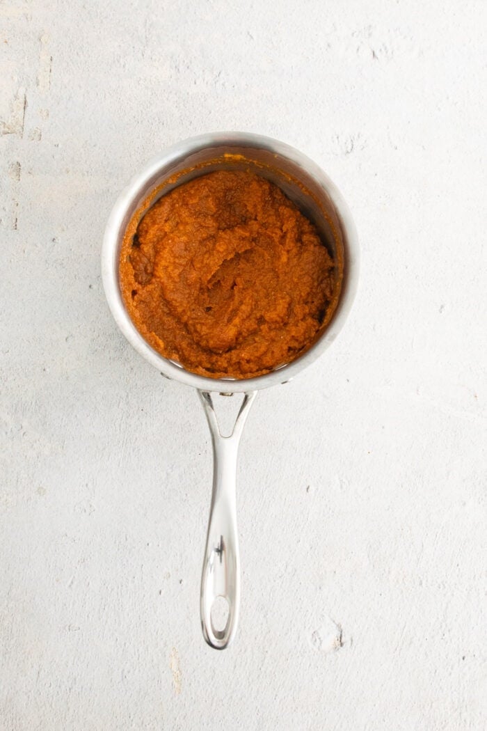 This Pumpkin Spice Latte has a base of pumpkin sauce sweetened with maple sugar that's mixed with strong espresso and topped with frothy milk. Spiced pumpkin sauce warms in a pot.