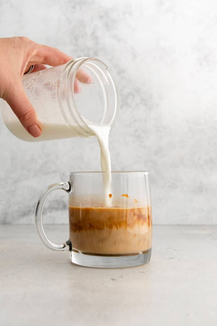 This Pumpkin Spice Latte has a base of pumpkin sauce sweetened with maple sugar that's mixed with strong espresso and topped with frothy milk. Steam milk is poured into the glass of espresso and pumpkin sauce.