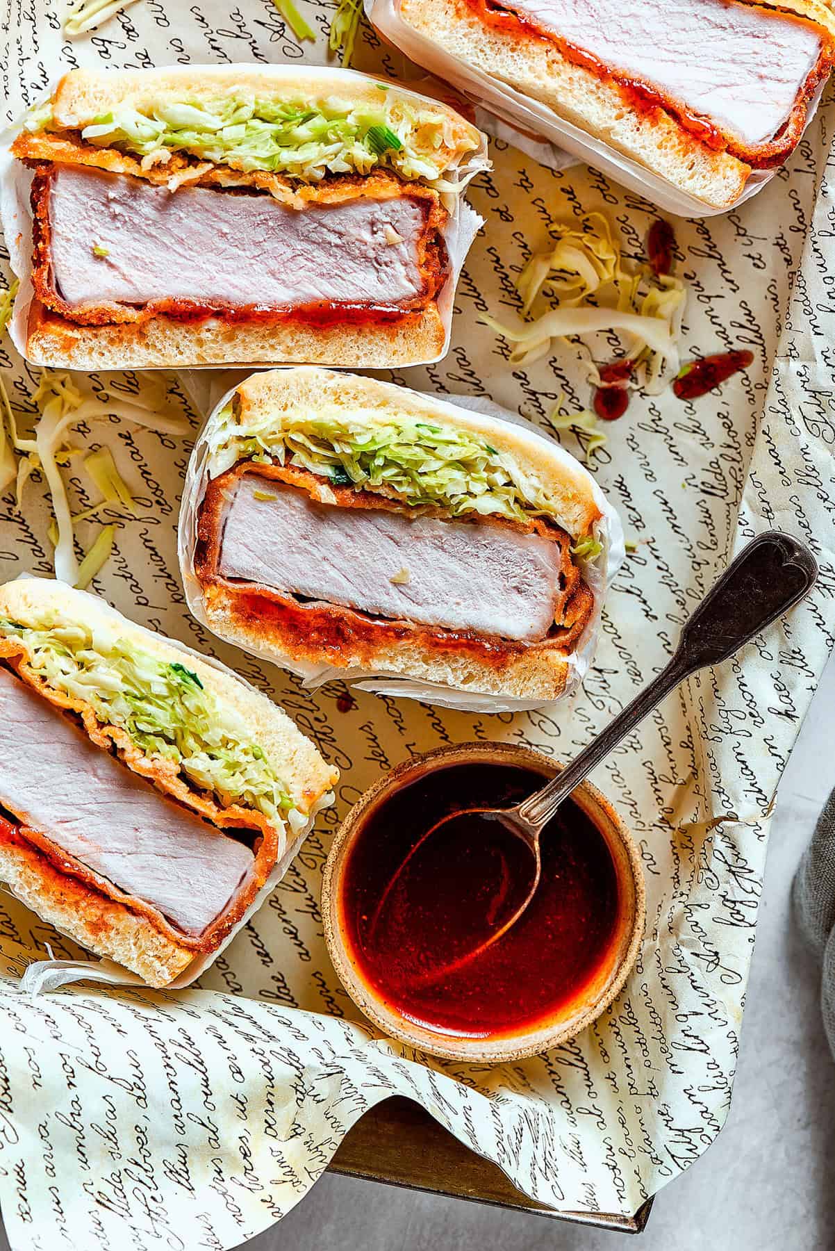 a tray of sliced pork katsu sandwiches with a bowl of sauce