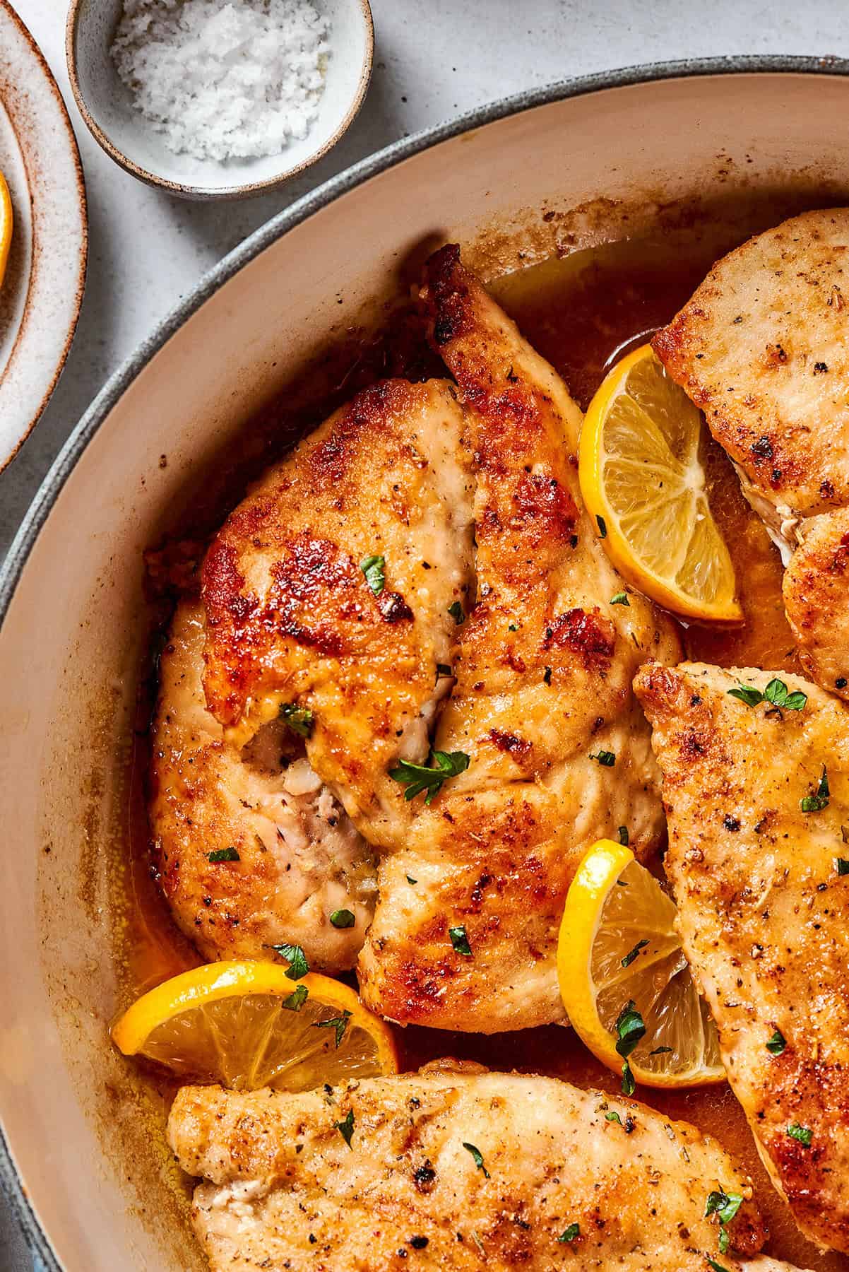 This juicy and tender Lemon Pepper Chicken recipe punches up ordinary chicken with a burst of bright, fresh lemon and a simple sauce. overhead, close photo of chicken breasts in a skillet with lemon and pepper