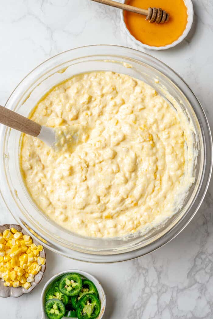 the batter mixed together for Jiffy corn casserole, in a clear mixing bowl
