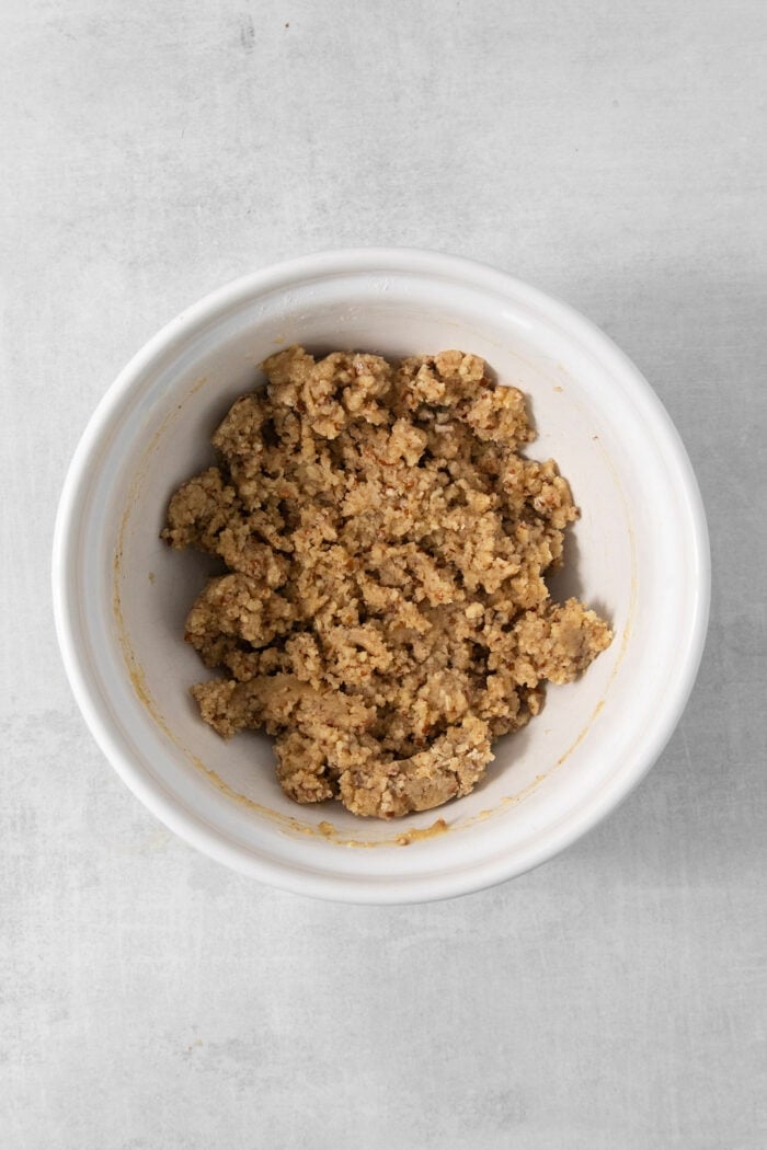 This chilled possum pie recipe with three layers of chocolate, cream cheese, and whipped cream goodness will be your new favorite dessert. The crumbly pecan crust mixture in a bowl.