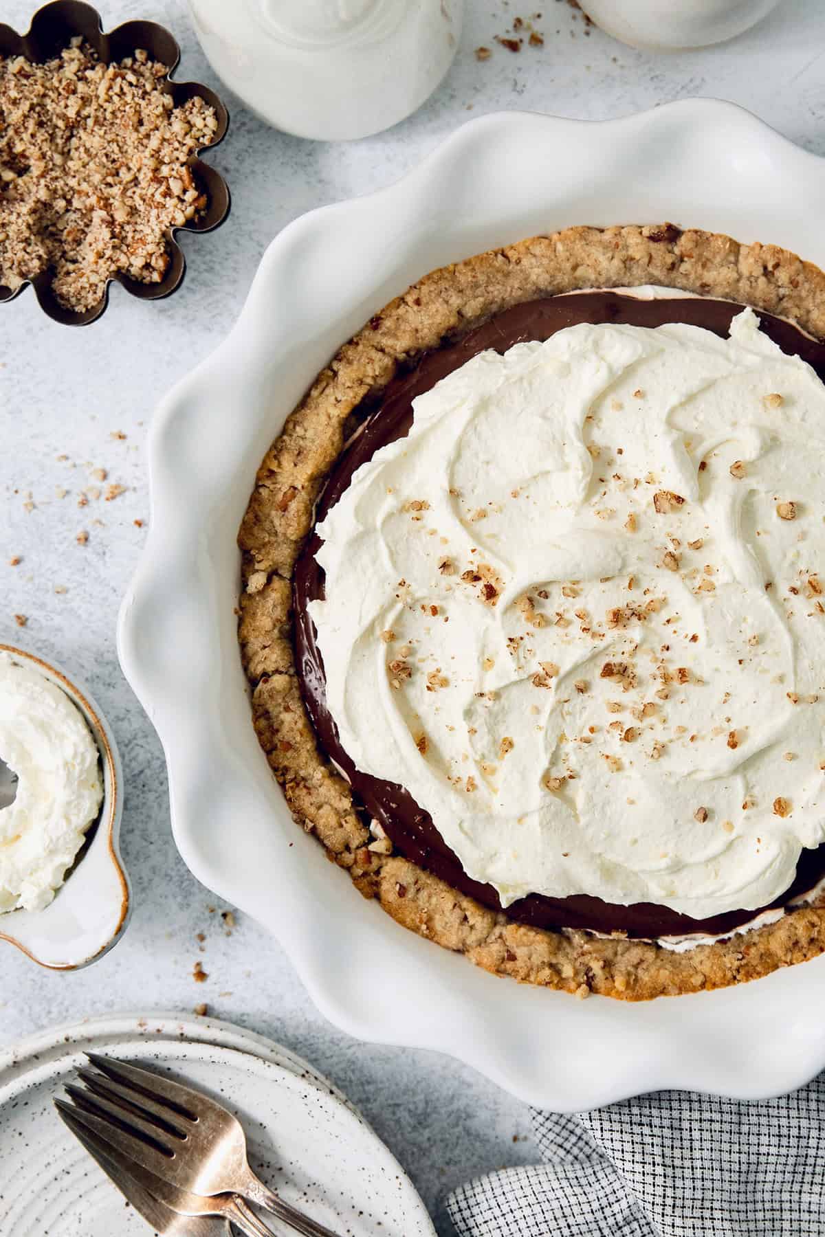 This chilled possum pie recipe with three layers of chocolate, cream cheese, and whipped cream goodness will be your new favorite dessert. Angled photo of chocolate-cream cheese pie with fluffy whipped cream on top.