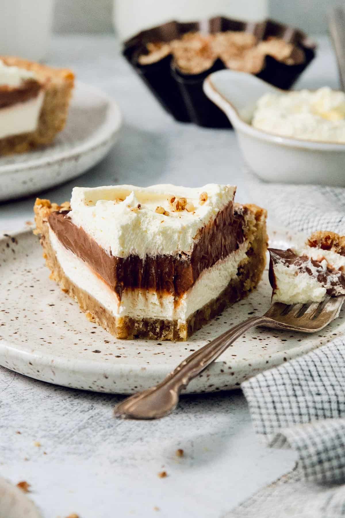 This chilled possum pie recipe with three layers of chocolate, cream cheese, and whipped cream goodness will be your new favorite dessert. A slice of layered possum pie with whipped cream on top.