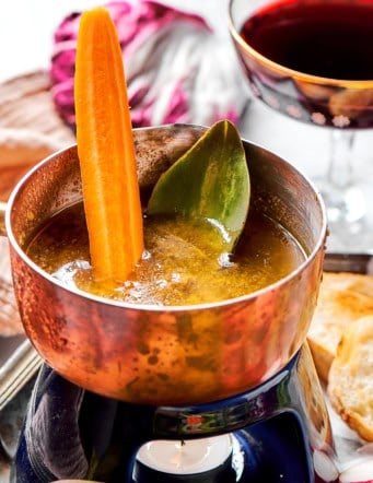 a small pot of bagna cauda with a candle burning underneath, plus fresh vegetables for dipping