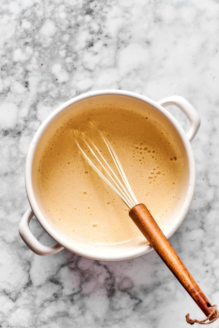 whisking eggnog mixture in a white pot