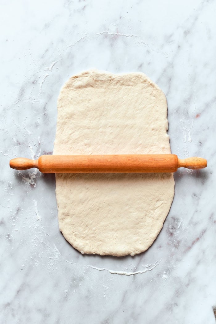 Homemade pizza bites tuck pepperoni and gooey mozzarella into seasoned pizza dough, then they're baked with even more cheese on top. Yum! Rolling out pizza dough on marble work surface