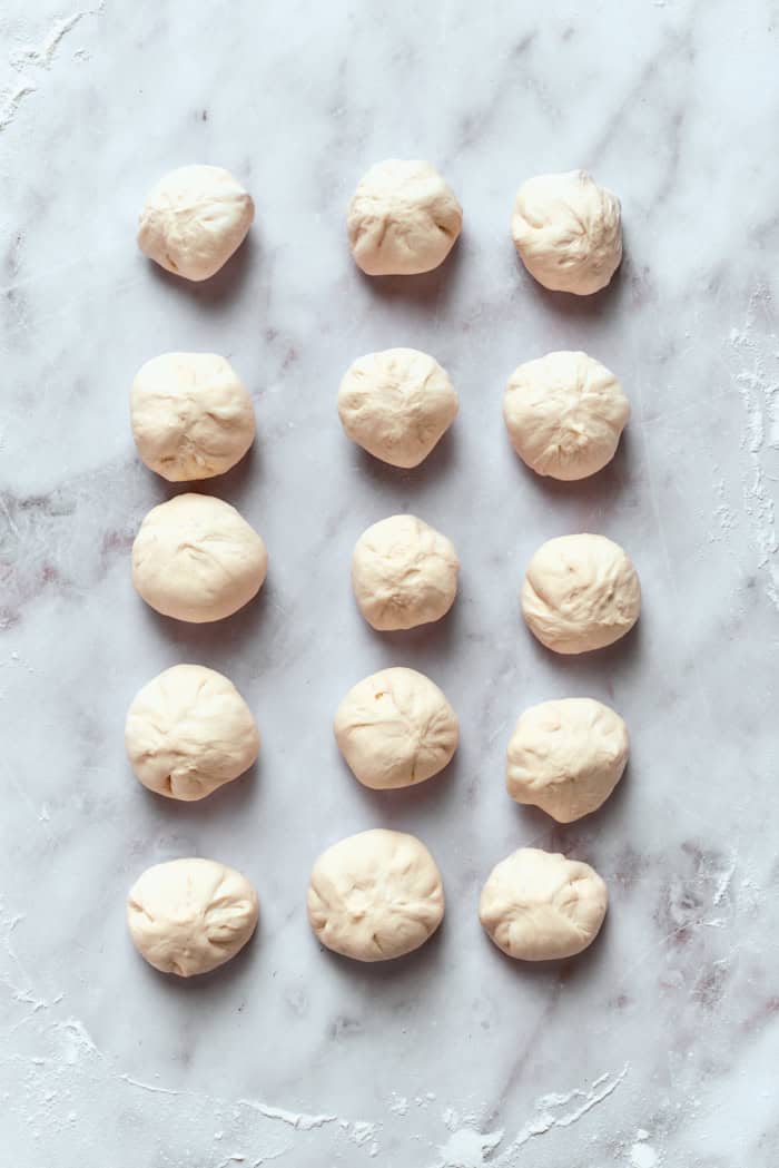 Homemade pizza bites tuck pepperoni and gooey mozzarella into seasoned pizza dough, then they're baked with even more cheese on top. Yum! Raw pizza bites on marble work surface