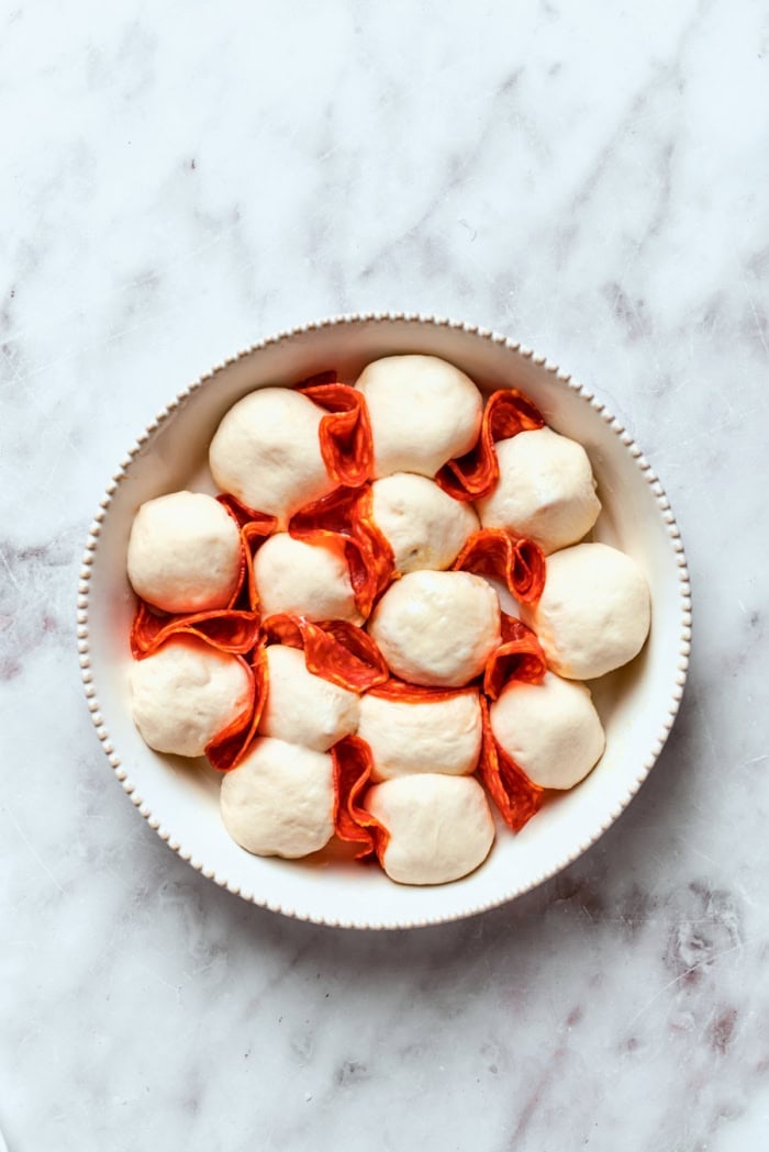 Homemade pizza bites tuck pepperoni and gooey mozzarella into seasoned pizza dough, then they're baked with even more cheese on top. Yum! Pizza bites with chorizo tucked in between before baking