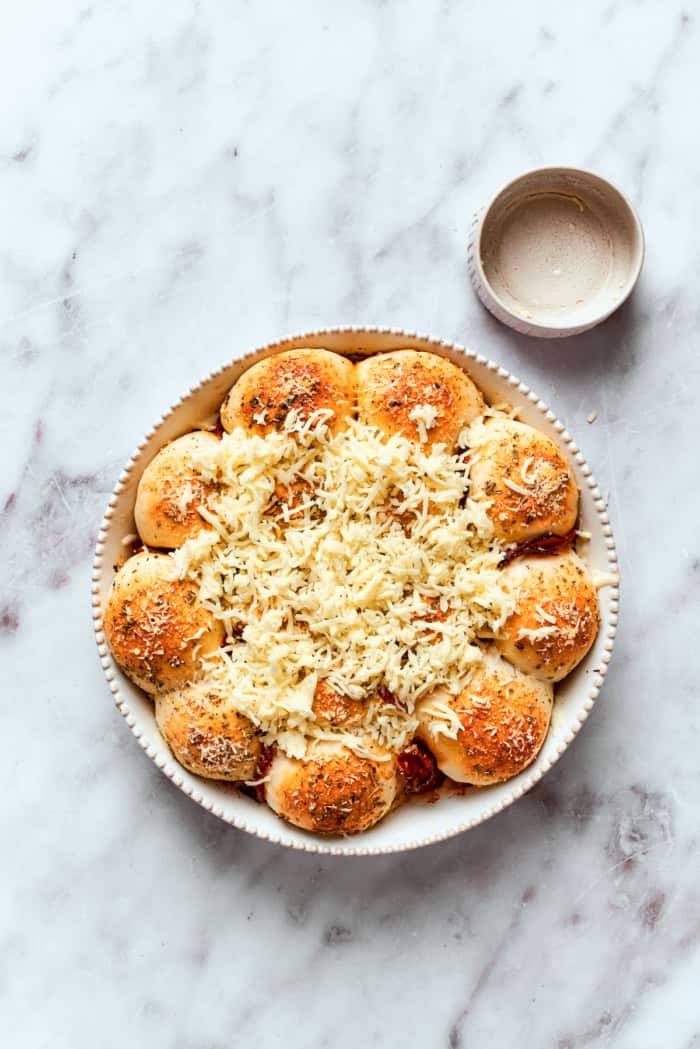 Shredded mozzarella added to baked pizza bites