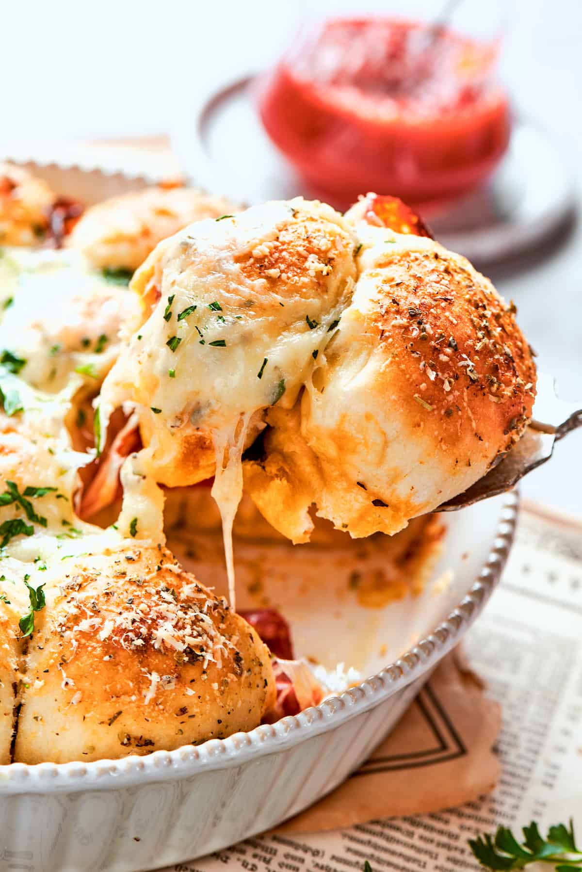 Homemade pizza bites tuck pepperoni and gooey mozzarella into seasoned pizza dough, then they're baked with even more cheese on top. Yum! Spoon lifting pizza bite from baking dish