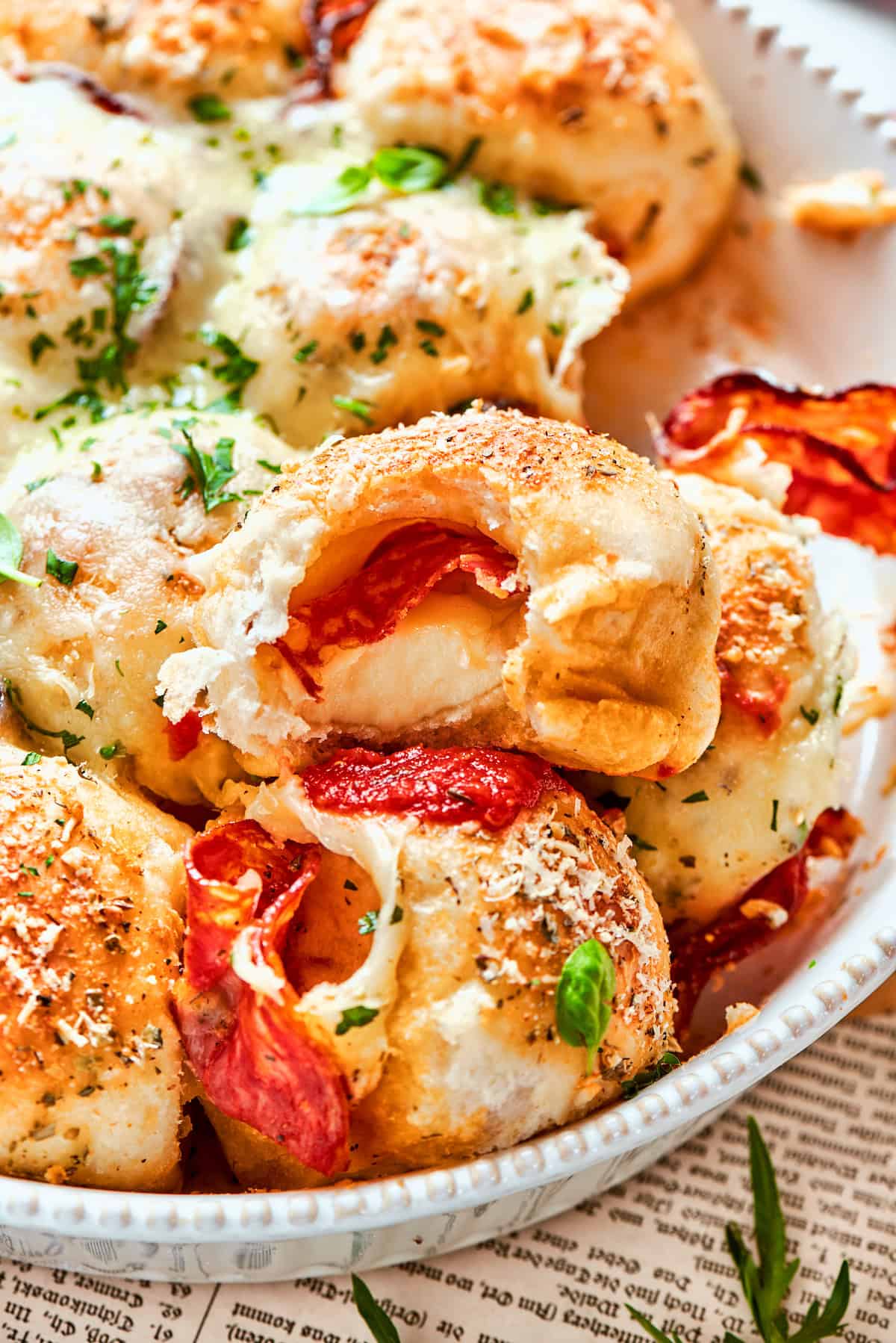 Homemade pizza bites tuck pepperoni and gooey mozzarella into seasoned pizza dough, then they're baked with even more cheese on top. Yum! Pizza bites in dish, with bitten piece on top to show interior