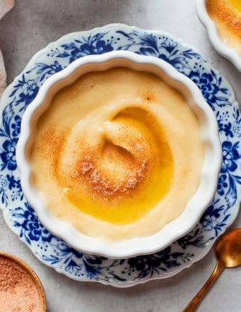 Norwegian rommegrot in a white bowl, with cinnamon-sugar and melted butter