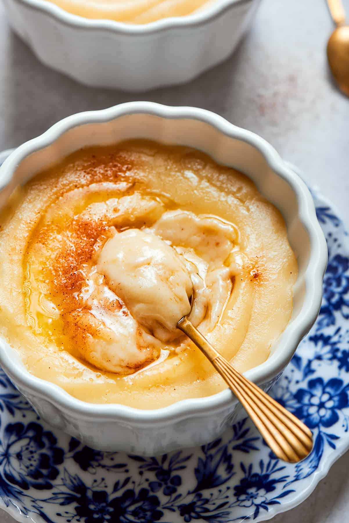 Rømmegrøt is a warmed Norwegian porridge similar to rich pudding, served with a drizzle of melted butter and a good sprinkling of cinnamon! a spoon in a bowl of Norwegian rommegrot