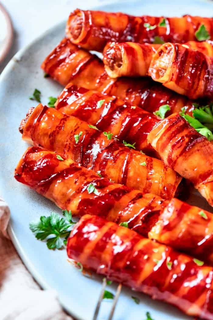 This baked shotgun shells recipe is a simpler version you can make in the oven — no smoker required! Smoky, savory, spicy and irresistible! Bacon-wrapped shotgun shells on platter