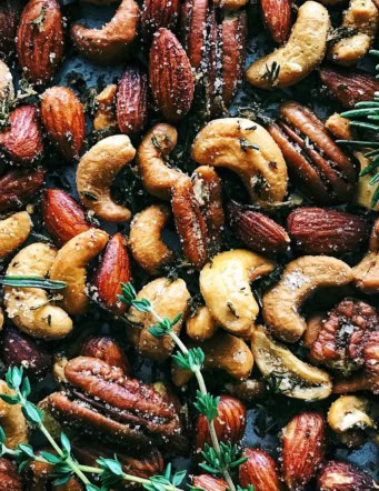 a pan of spiced nuts with fresh rosemary and thyme