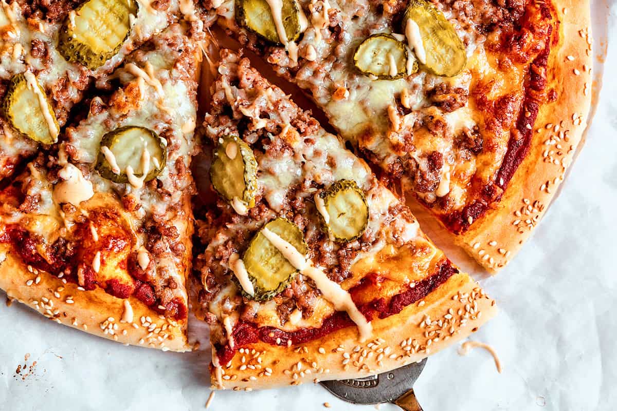 taking a slice of cheeseburger pizza