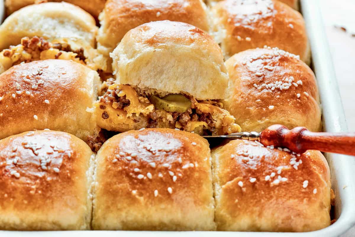 Homemade Cheeseburger Sliders star tender ground beef topped with plenty of melted cheddar cheese served on sweet rolls. a pan of homemade cheeseburger sliders