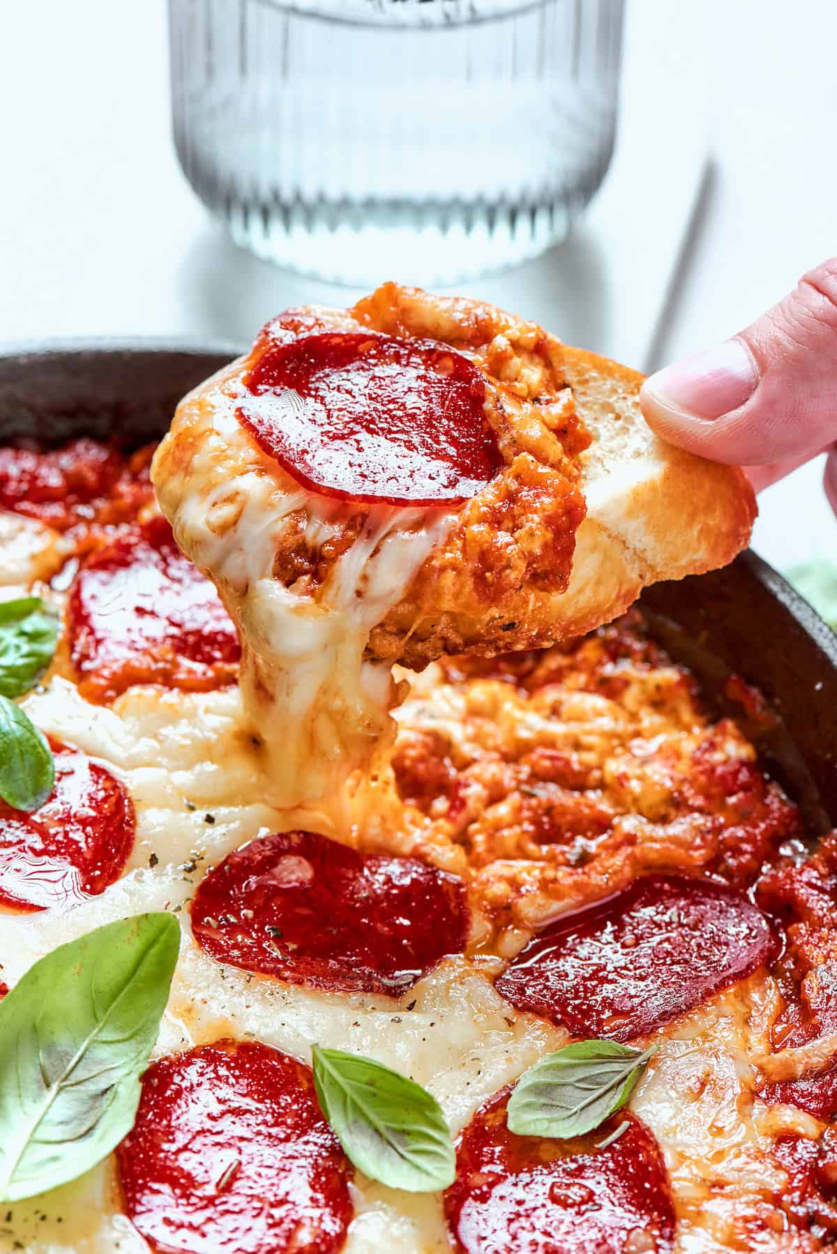 dipping into baked pizza dip with a slice of baguette