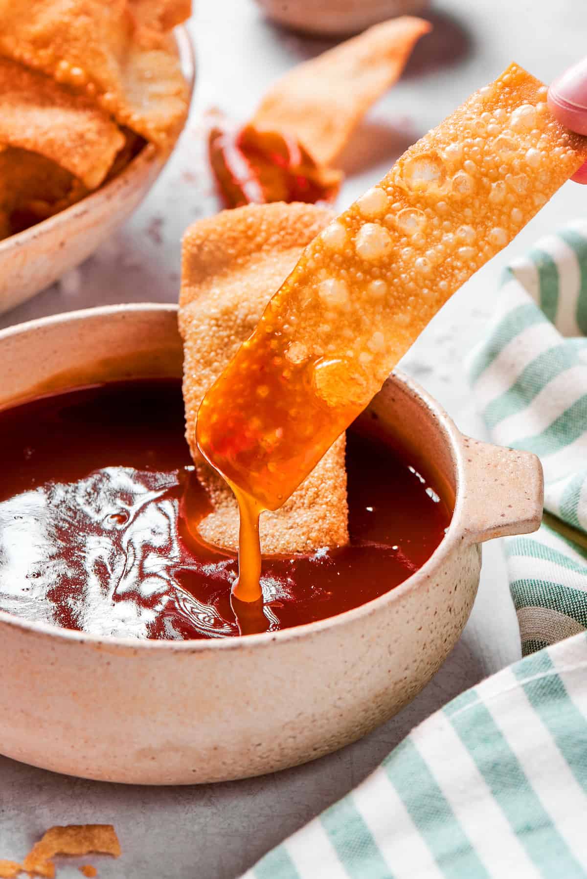 These easy homemade wonton chips have the most fantastic crunch and a salty flavor that makes them pair with just about anything! Dipping wonton chip into sweet and sour sauce