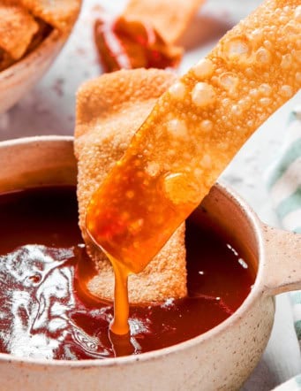 dipping a homemade wonton chip into sweet and sour sauce