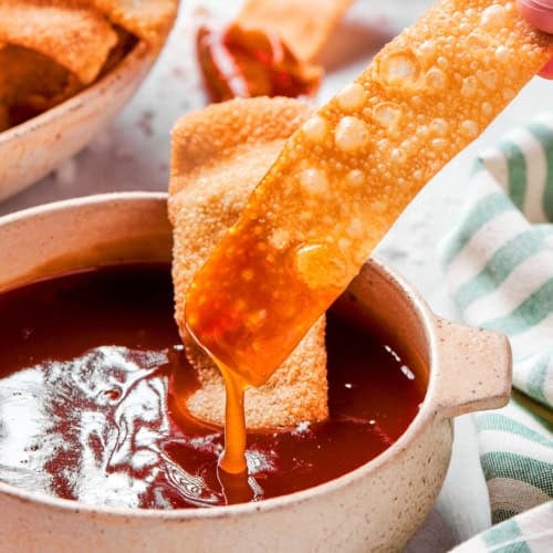 dipping a homemade wonton chip into sweet and sour sauce