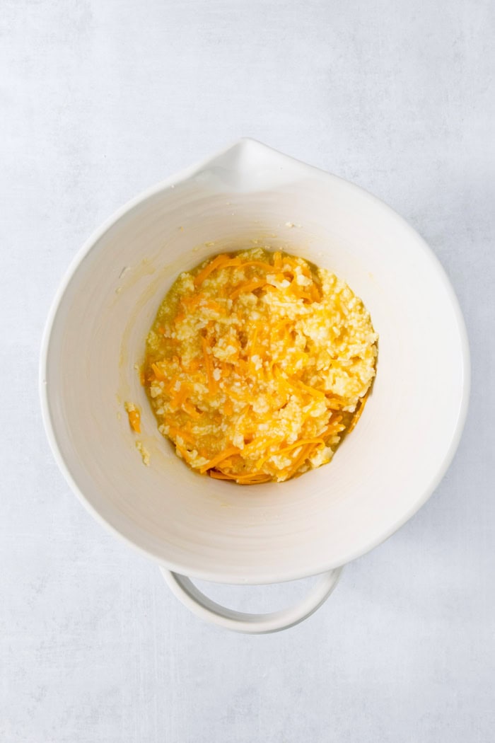 This Colombian Pandebono recipe is fantastically cheesy, surprisingly easy, and irresistibly tender and fluffy. So delicious! Cheese added to bowl for pandebono