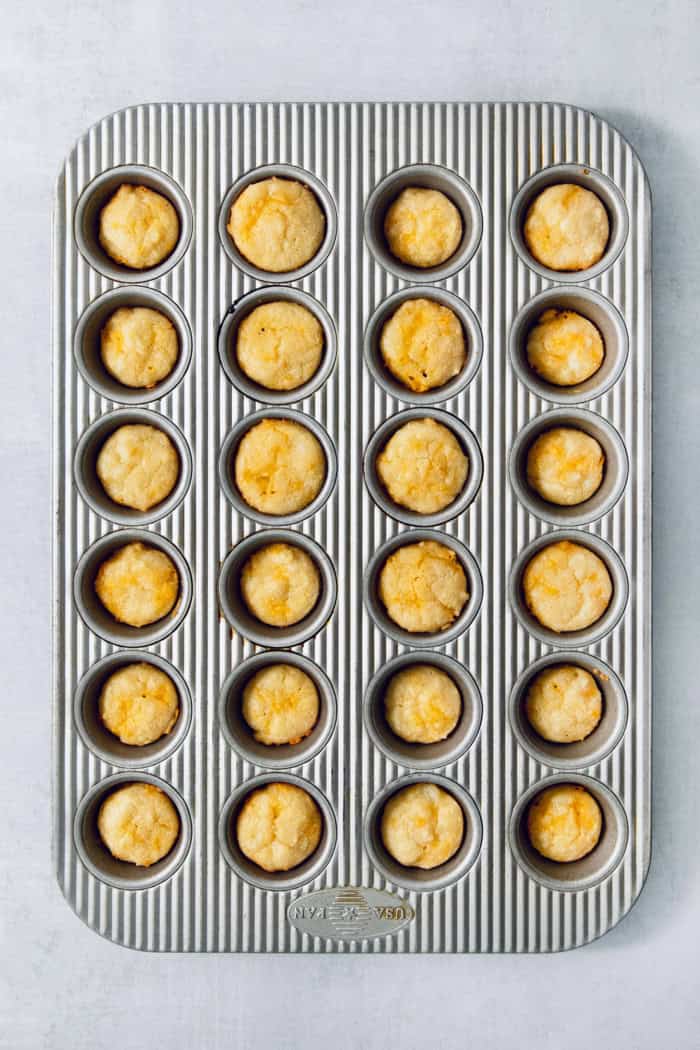 This Colombian Pandebono recipe is fantastically cheesy, surprisingly easy, and irresistibly tender and fluffy. So delicious! Overhead view of pandebono in mini muffin pan