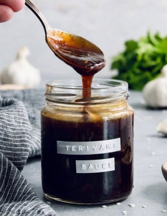 Drizzling homemade teriyaki sauce from spoon into jar