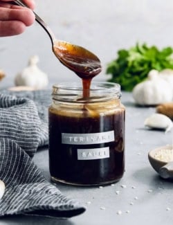 Drizzling homemade teriyaki sauce from spoon into jar