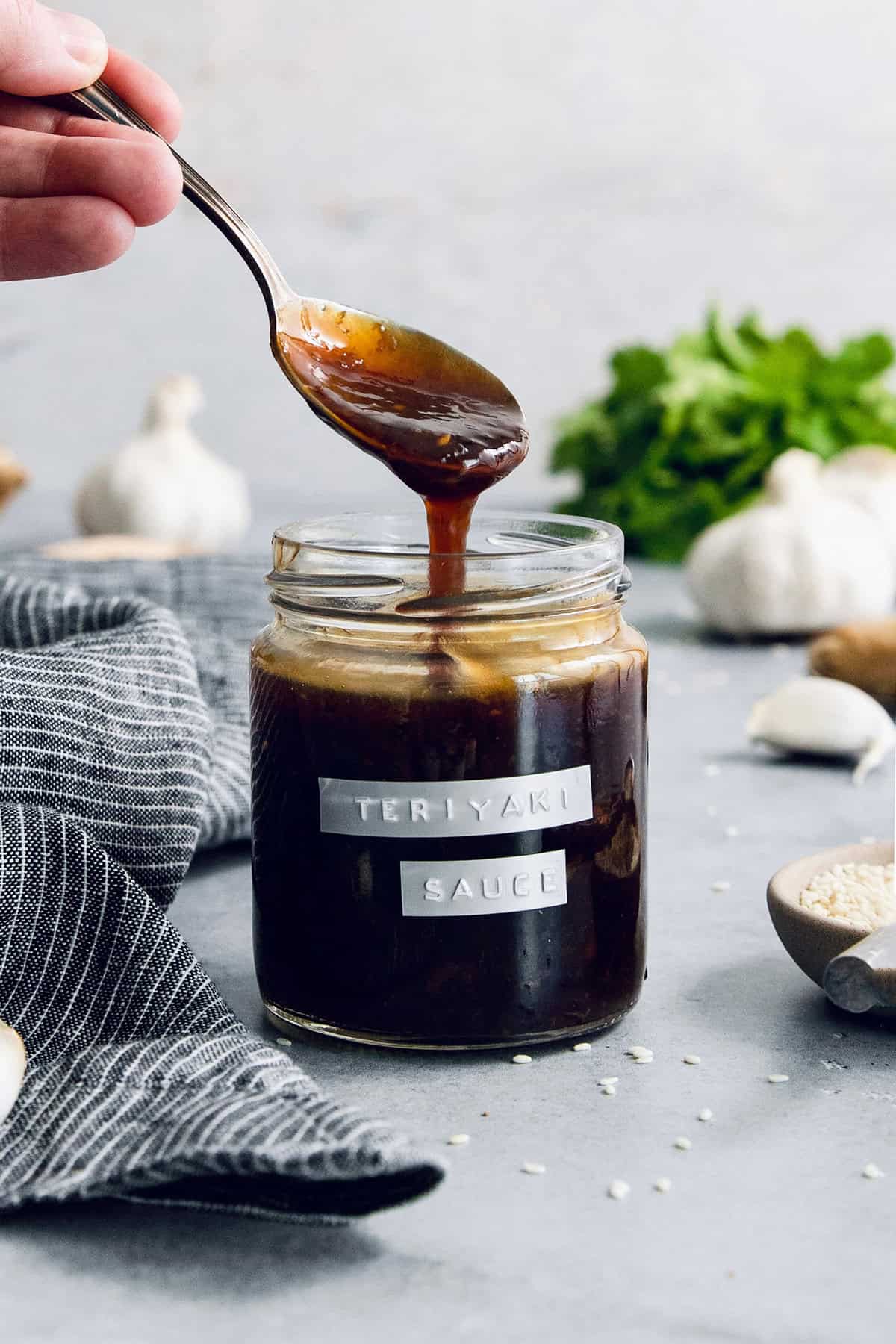 Drizzling homemade teriyaki sauce from spoon into jar