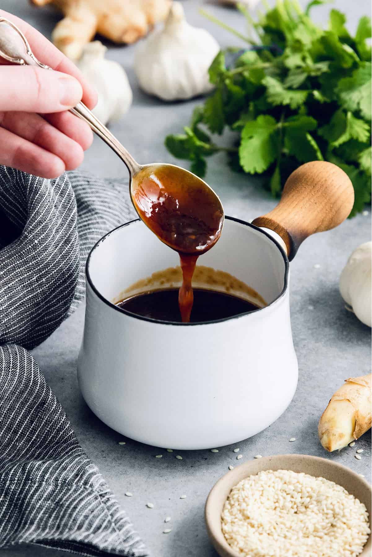 Drizzling teriyaki sauce from spoon into pan
