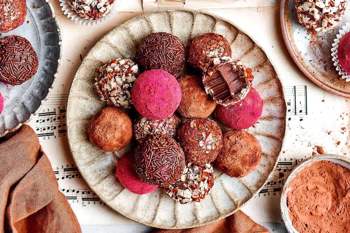 Melt-in-your-mouth Chocolate Truffles are an indulgence worth making from scratch. This easy recipe calls for only 6 simple ingredients! chocolate truffles rolled in a variety of coatings, on a cream colored plate