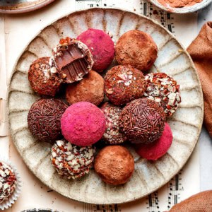 chocolate truffles rolled in a variety of coatings, on a cream colored plate