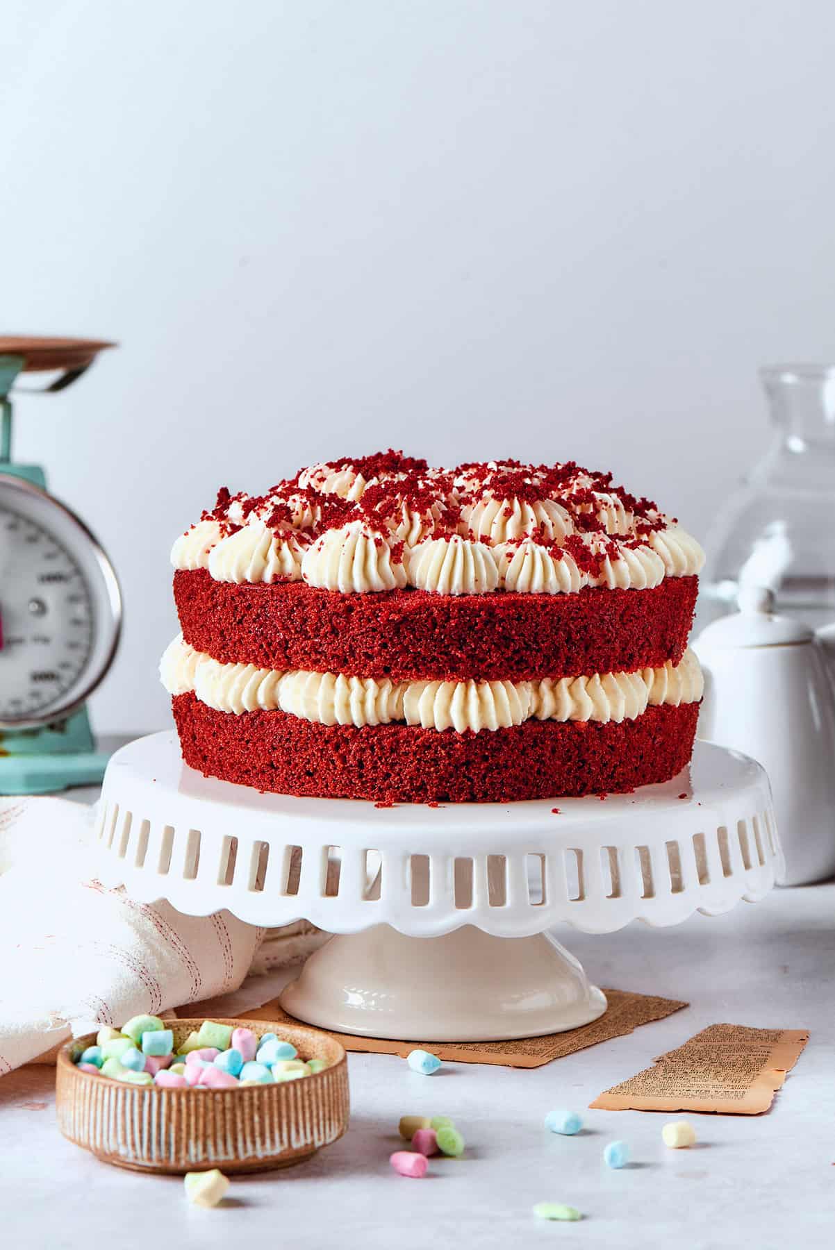 a double layer red velvet cake with cream cheese frosting on a white pedestal