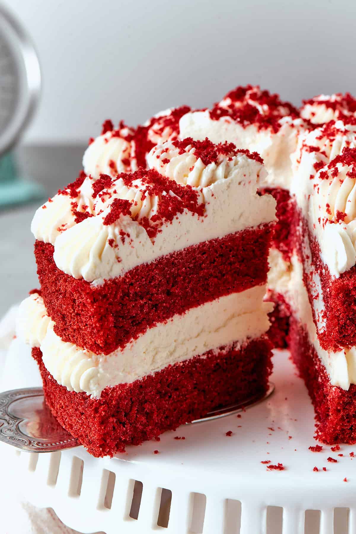 removing a piece of double layer red velvet cake with cream cheese frosting