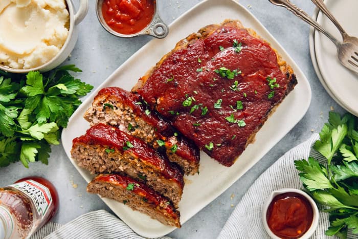 This Air Fryer Meatloaf gives you a classic comfort food meal — without the hassle of an oven. Tender and juicy, with the perfect glaze! Overhead view of air fryer meatloaf on platter with three slices cut